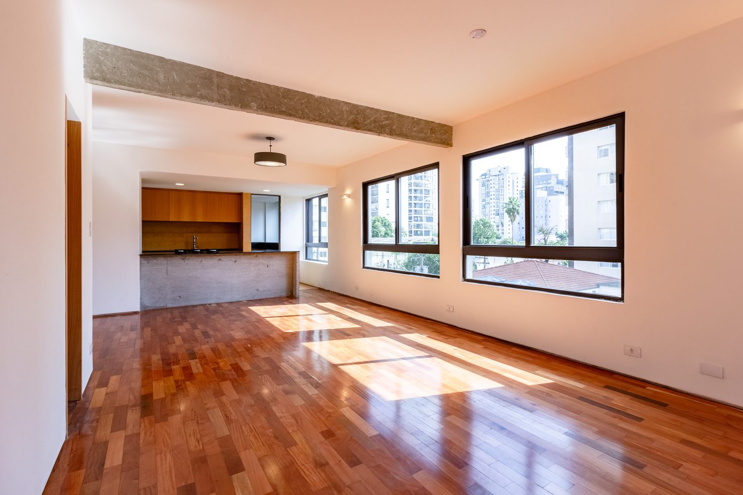 Área social do apartamento modelo, com a cozinha ao fundo