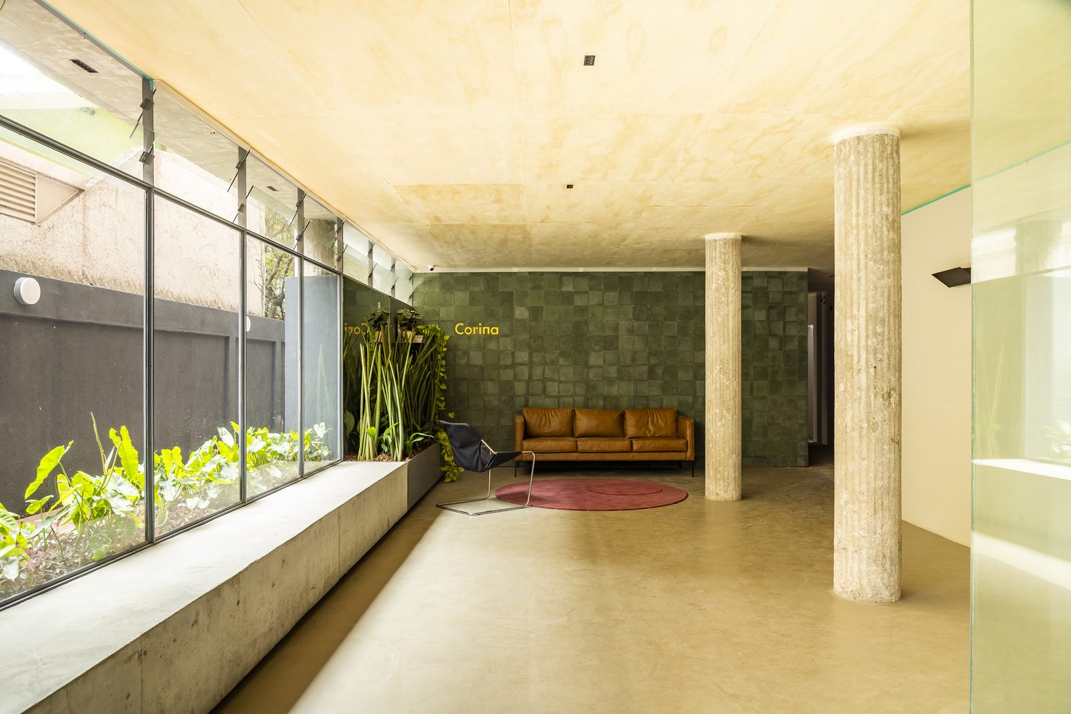 Hall de entrada do Corina, com pilares, pé-direito alto e jardim lateral